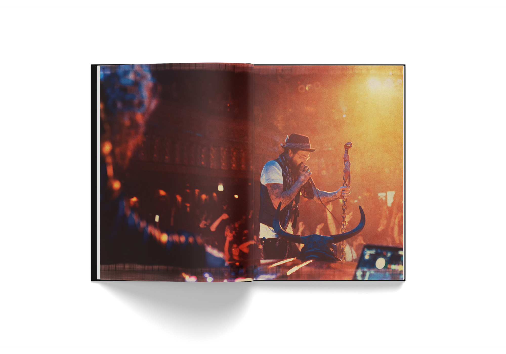 Open hardcover book "Yelawolf 51/50" featuring live concert photo of rapper Yelawolf on stage with microphone and bull skull prop in warm lighting