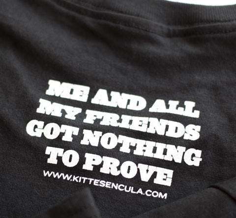 Close-up of black Kittesencula Mescal Tee with white bold text "ME AND ALL MY FRIENDS GOT NOTHING TO PROVE" printed on front