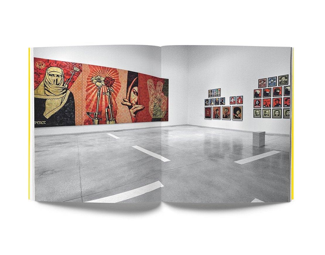 Open book showing "Cross The Streets" street art exhibition with vibrant urban artworks inside a modern gallery space