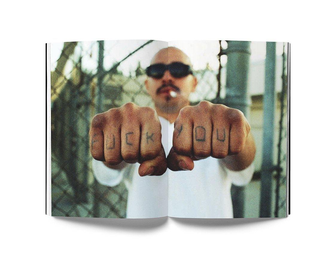 Open book spread showing a portrait of a man with tattoos on his knuckles reading "fuck you," photographed in a gritty urban setting, illustrating Estevan Oriol's LA Portraits photography collection.