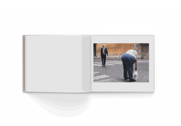 Open photo book showing street photography by Mohamed Keita featuring two people on a city sidewalk in Rome