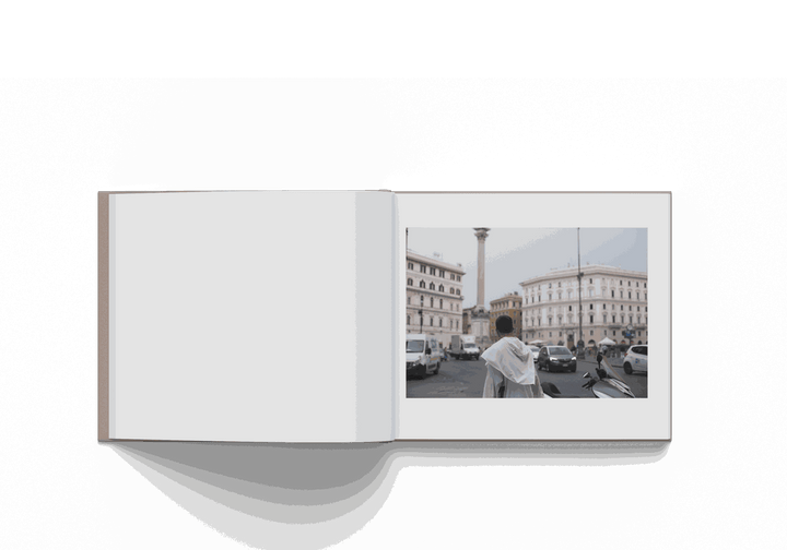 Open photo book "Mohamed Keita Rome 10/20" showing a man facing Rome cityscape with historical buildings and traffic.